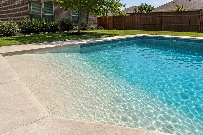 Backyard pool with a gently sloping beach entry at one end