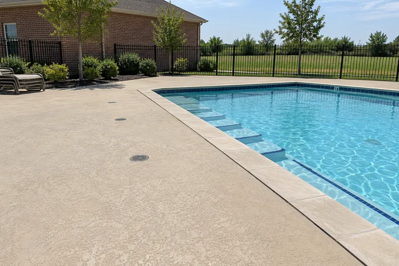 Wide textured deck with drains around a community pool
