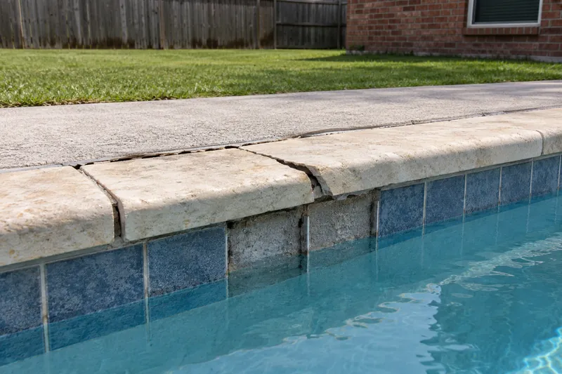 Cracked, lifted coping stone and an open joint at the pool deck