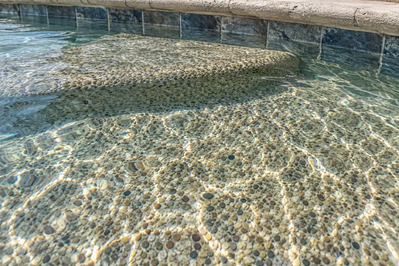 Pebble pool finish in tan and gray stones under clear water