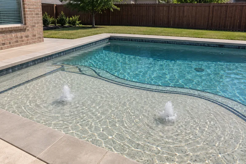 Wide sun shelf with two bubblers in a backyard pool