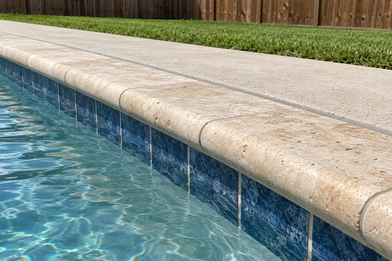 Travertine bullnose pool coping with a sealed joint to the deck